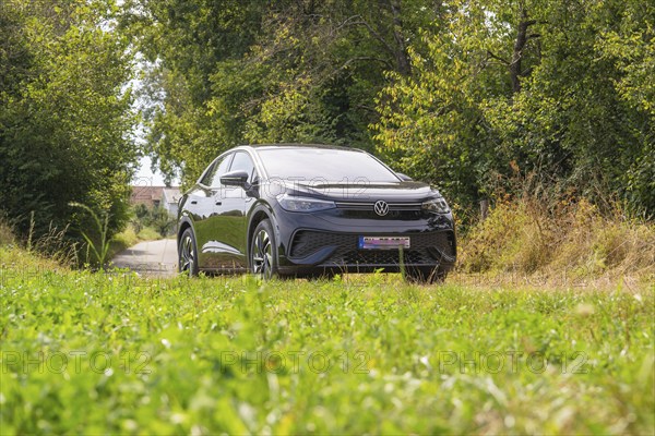 Black SUV parked on a rural road, surrounded by lush vegetation and summer atmosphere, VW ID5