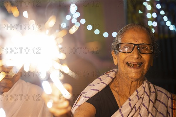 An elderly woman of Pramod Talukdar Memorial Old Age Home burn sparkler crackersas she celebrate