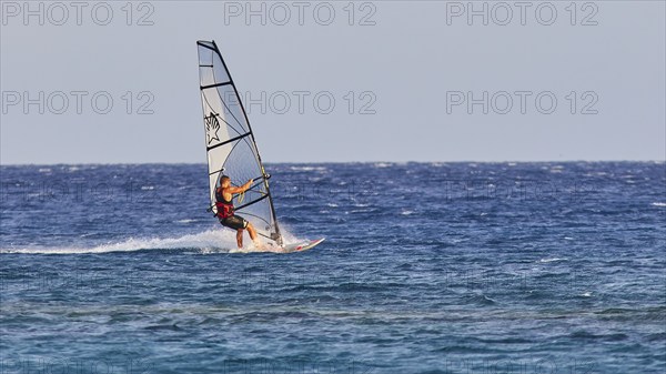 A windsurfer with a stylish sail glides over the sea surface, windsurfer, Meltemi windsurfing spot,