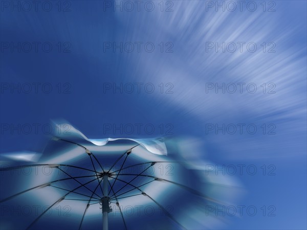 Parasol in front of a blue sky with clouds, zoom effect