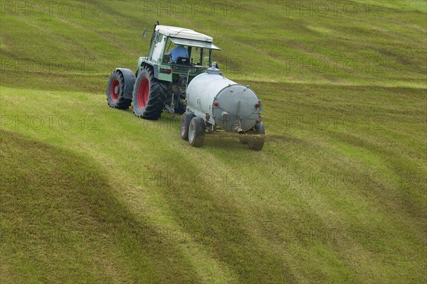 Tractor spreading liquid manure on a green field, meadow, Bavaria, Germany, Europe