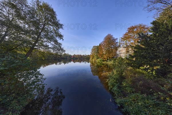 Mill pond with trees against blue sky, reflections on the water surface, Hanseatic city of Lübeck,