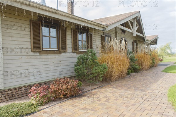 Modern restaurant with green lawn, tile path and landscape design with ornamental grasses and