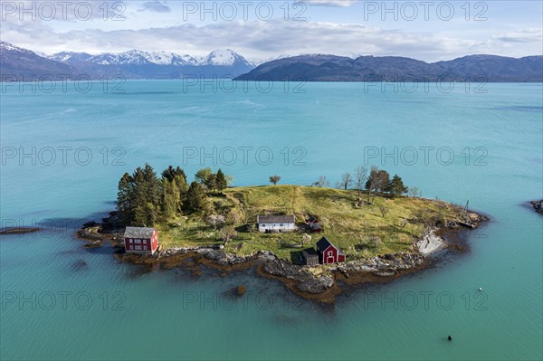 Aerial view of typical red houses on an island in the Hardangerfjord, mountain range in the back,