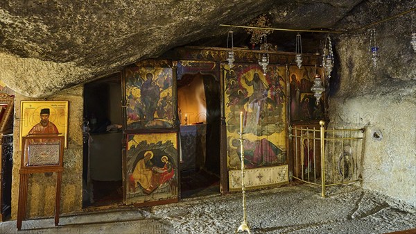 Orthodox church in a stone cave with iconostasis, sacred images and candles that create a spiritual