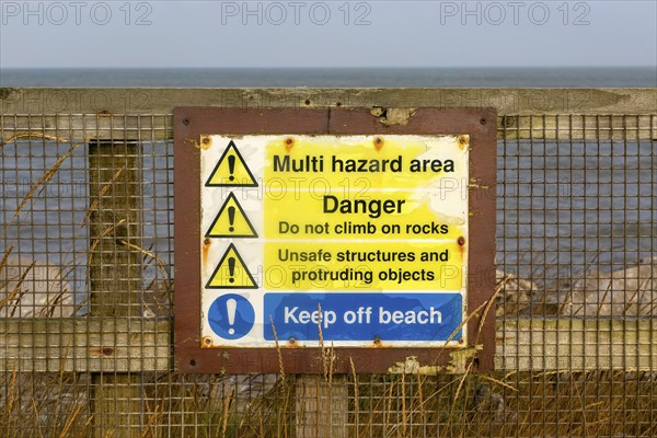 Environment Agency warning danger sign above rock armour, East Lane, Bawdsey, Suffolk, England, UK