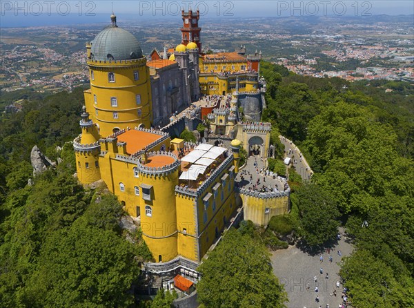 Historic castle in yellow on a hill with an impressive view and surrounded by forest, aerial view,