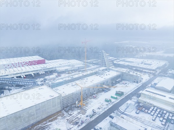Snow-covered industrial area with crane and construction site in foggy surroundings, Häfele,