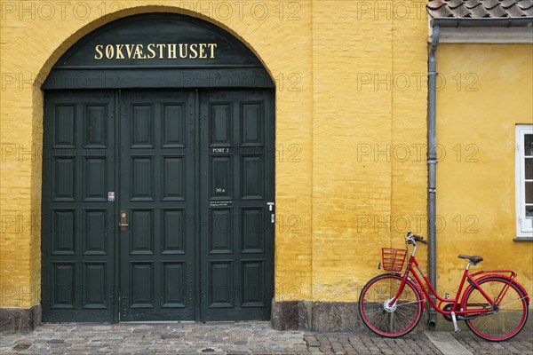 Red bicycle in front of yellow wall, entrance to heritage-protected building Søkvæsthuset, former