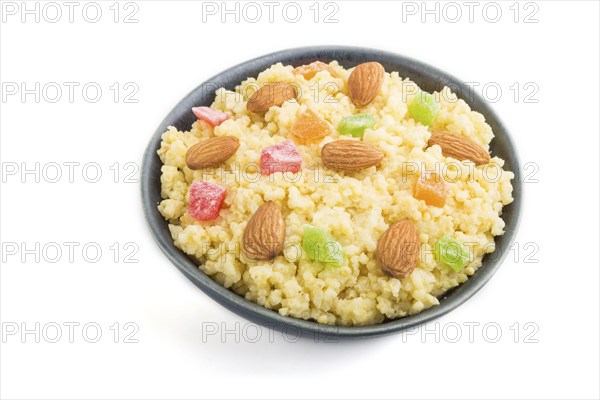 Millet porridge with candied fruits and almonds in blue ceramic bowl isolated on white background.