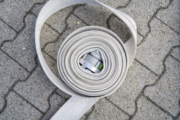 Coiled fire hose with metal buckle on paved ground, fire brigade, Enzklösterle, Black Forest,