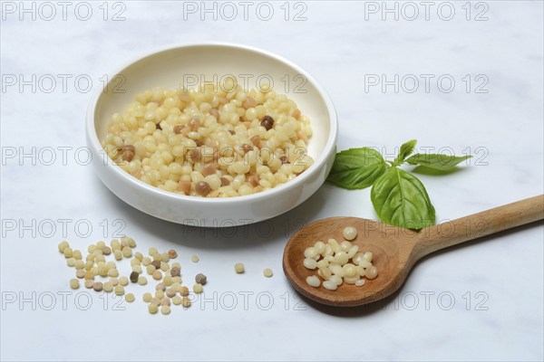 Cooked fregola in bowl with wooden spoon, pasta variety from Sardinia, Italy, Europe