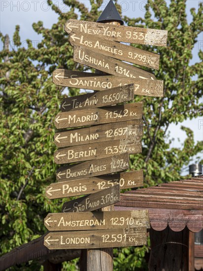 Signpost showing directions to major world cities, Plaza del Arma, Futaleufu, Chile, South America