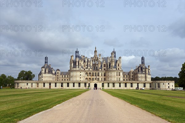 Large historic castle with many towers and decorations, situated along a long path, surrounded by