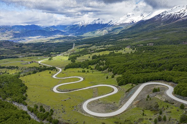Road Carretera Austral winding down into the valley of Villa Cerro Castillo, snowcapped mountains
