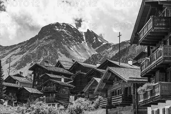 Nested old wooden houses, in the background the summit of the mountain Scex de Marenda, historic