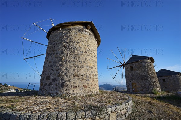 Two old stone windmills under a clear blue sky in a natural landscape, windmills, on a ridge, above