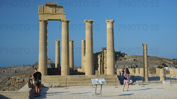Tourists visit the ancient ruins of Lindos under a bright blue sky, Acropolis of Lindos, morning