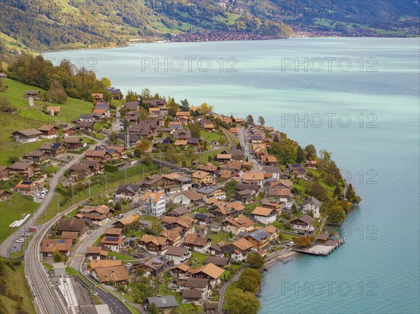Hilly village with houses and streets on the edge of a lake, surrounded by mountains, Lake Brienz.