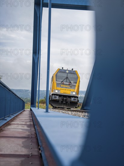 Train approaching from behind blue subway on rails, track construction, rail delivery for Hermann