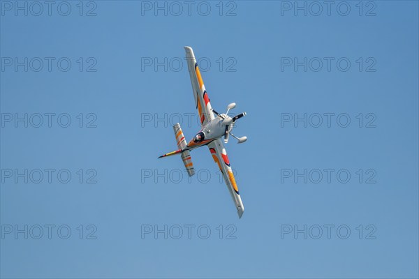 Stunt aerobatic plane performing stunts in blue sky. Concept of speed, difficulty, precision, risk,