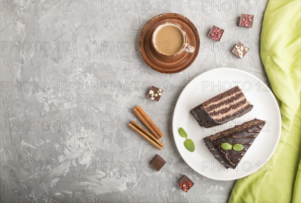 Homemade chocolate cake with milk cream and a cup of coffee on a gray concrete background with