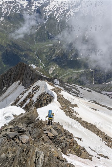 Mountaineer on a rocky ridge with snow, descent from the summit of the Schönbichler Horn, view of