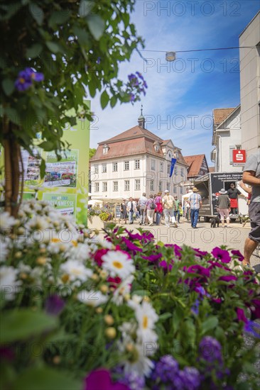 Street scene with a green flower arrangement in the foreground and people in an urban environment