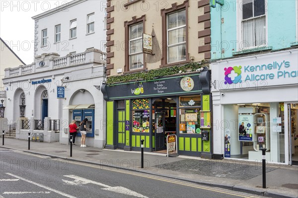 Shops and pharmacy along a busy street with mixed historic and modern facades, Tralee