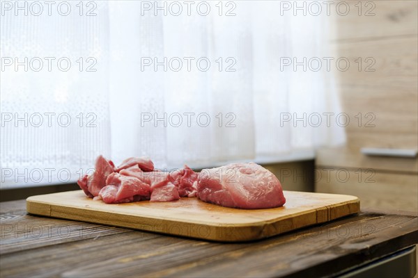 Raw pork shoulder on wooden cutting board in the kitchen