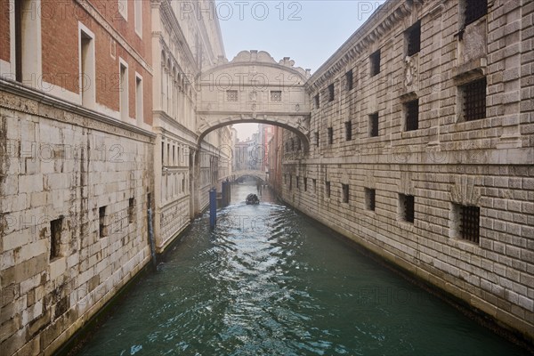 View from 'Ponte della paglia' on the bridge 'Bridge of Sighs' over a waterway before sunrise in