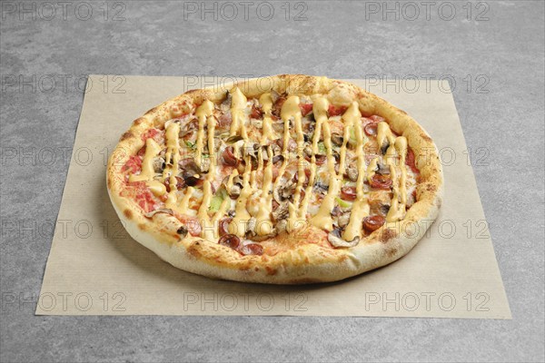 Pizza with thin sausage, jalapeno and champignon covered with mustard on parchment paper