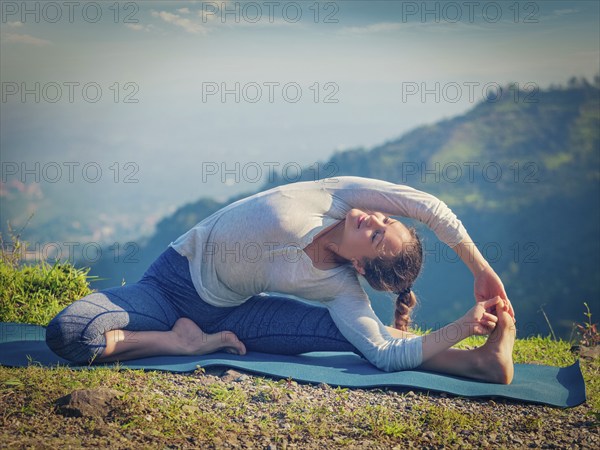 Yoga outdoors, young sporty fit woman doing Hatha Yoga asana parivritta janu sirsasana, Revolved