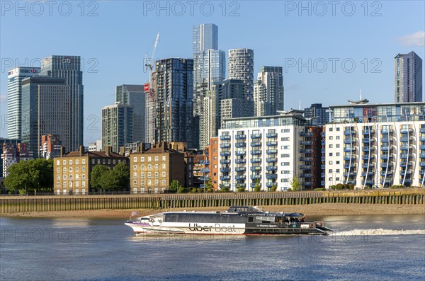 Uber boat water bus service passing Canary Wharf, Isle of Dogs, London, England, UK