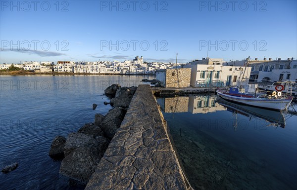 Harbour wall, local view of Naoussa town and blue sea, harbour with fishing boats and reflection,