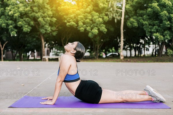 Sporty woman stretching her body doing cobra pose in a park. Athlete woman doing cobra pose in a