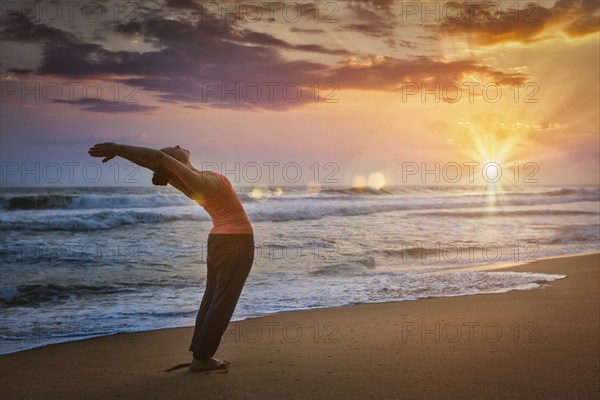 Young sporty fit woman doing yoga Sun salutation Surya Namaskar pose Hasta Uttanasana on tropical