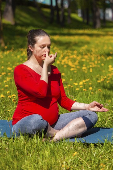 Pregnancy yoga exercise, pregnant woman doing pranayama breath exercise in Sukhasana easy yoga pose