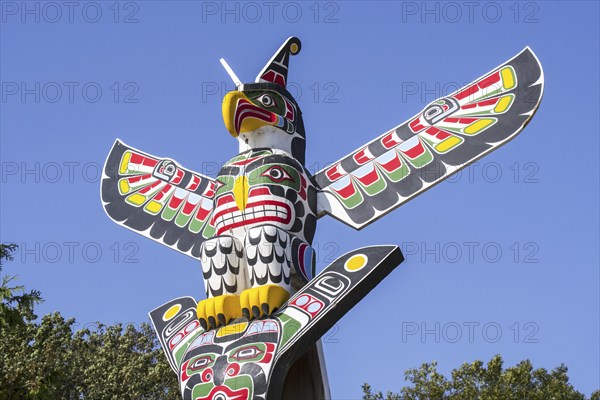Colourful wooden carved Canadian totem pole showing eagle against blue sky