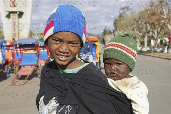 Young Malagasy girl carrying child on her back in the city Antsirabe, Vakinankaratra, Madagascar,