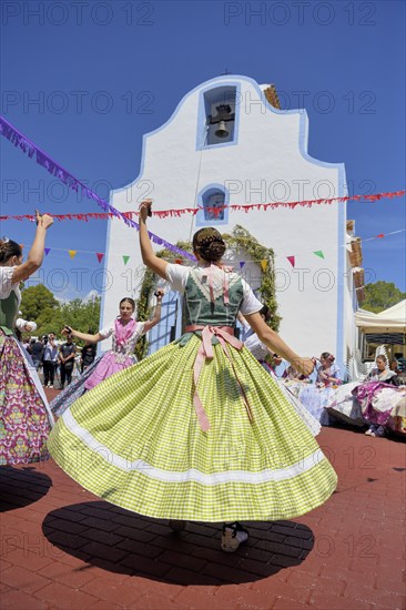 Women in traditional dress dance in front of the Ermita de San Vicent chapel, annual fiesta in