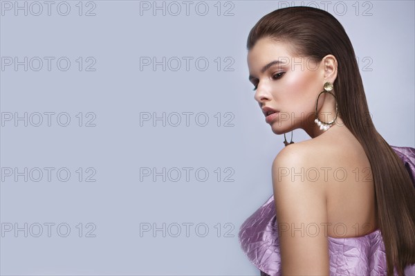 Beautiful fresh girl with classic make-up, smooth hair in a purple dress. Beauty face. Photo taken