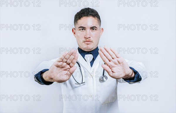 Doctor making a stop gesture with palms on white background. Latin doctor making a stop gesture