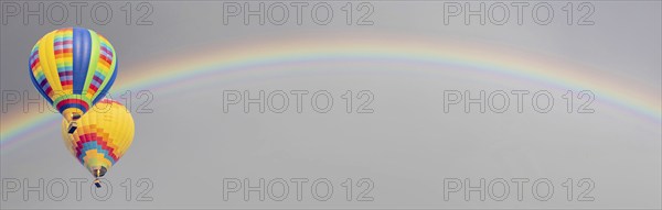 Hot air baloons drift with rainbow in the sky