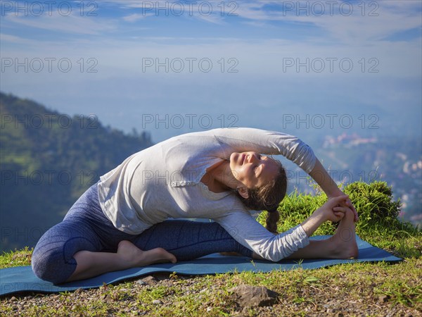 Yoga outdoors, young sporty fit woman doing Hatha Yoga asana parivritta janu sirsasana, Revolved