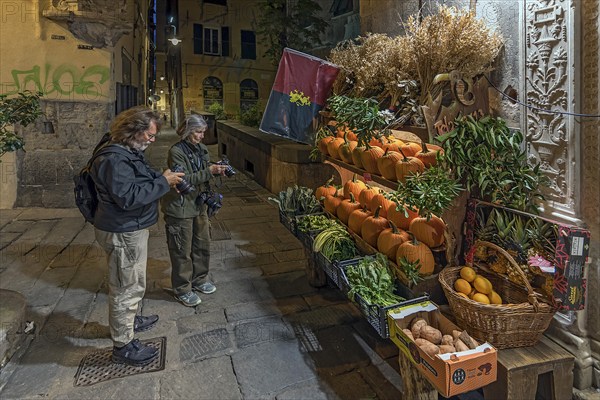 Tourists photographing a fruit shop in the evening in the historic centre, Genoa, Italy, Europe