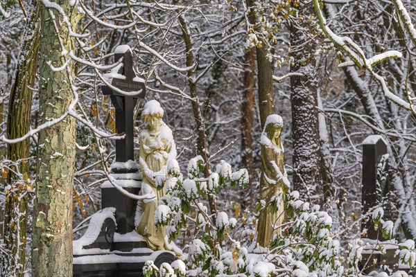 Graves with stone sculptures of mourning woman in the snow, Südwest-Kirchhof, historic cemetery in