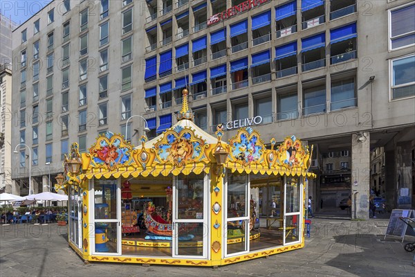 Children's carousel with painted Disney figures at the old harbour, behind skyscrapers, Genoa,