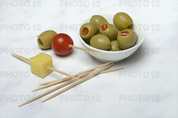 Green olives stuffed with pepper pieces, in bowl, toothpick with olive and cheese cube