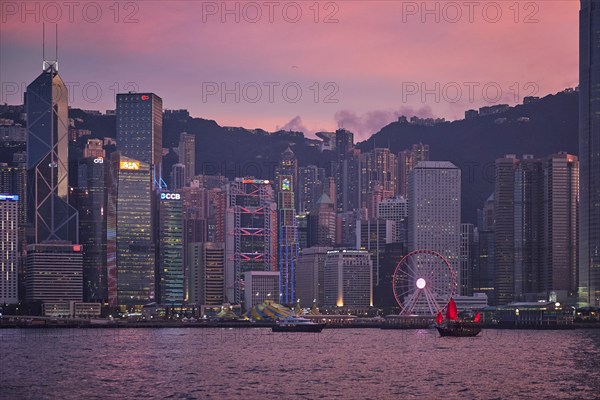 HONG KONG, CHINA, MAY 1, 2018: Tourist junk boat ferry with red sails and Hong Kong skyline